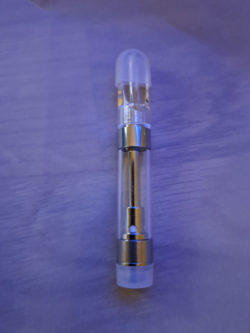A small V10 - PCTG Flat Tip -1ml glass bottle sits on top of a table.