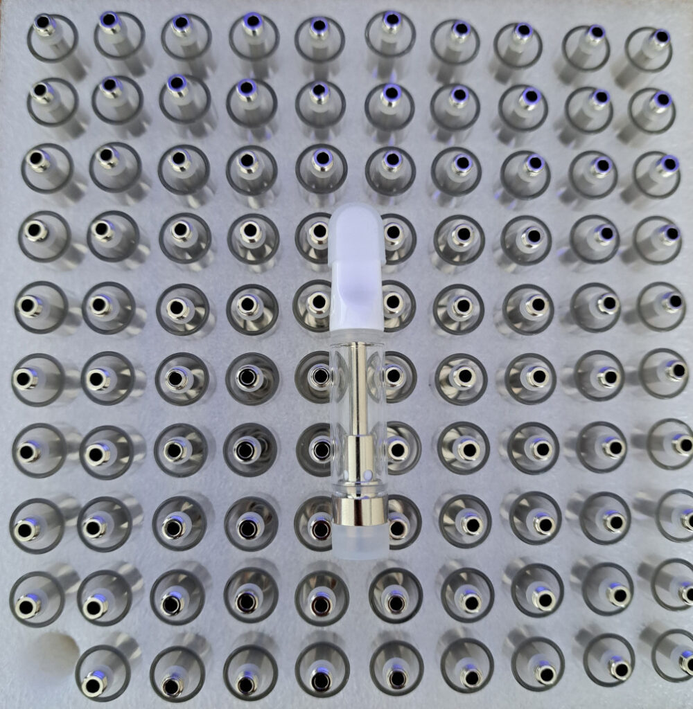A large number of V4 - White Tip - 1ml empty vape cartridges on a white plate.